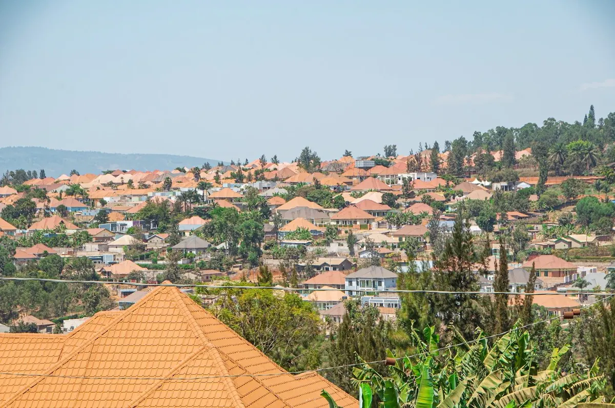 A Rwandan hillside neighbourhood with terracotta rooftops among green hills